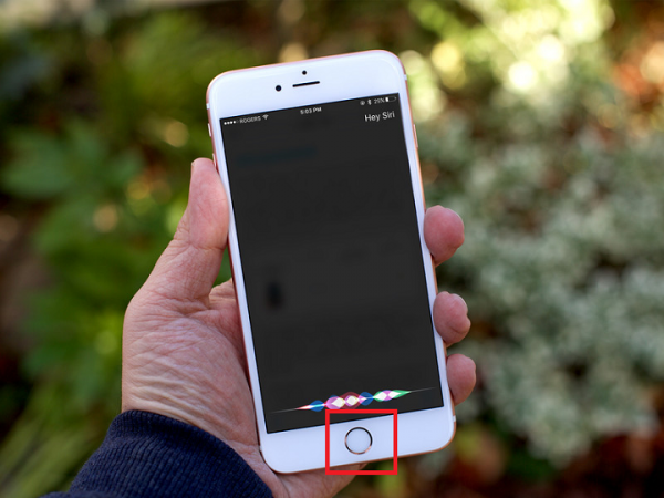 Hand holding an iPhone with Siri listening and the Home button highlighted