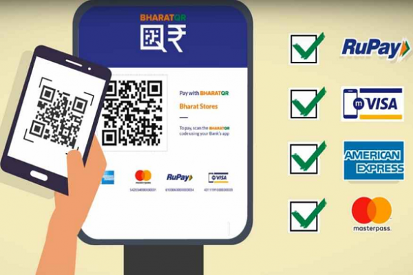 Phone scanning a BharatQR code on a shop stand to pay, with the supported card networks