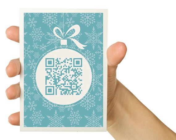 Hand holding a snowflake greeting card with a QR code in a bauble