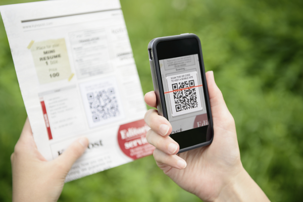 Phone scanning a QR code printed in a newspaper