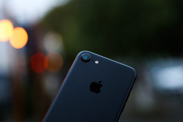 Back of an iPhone held up against blurred city lights